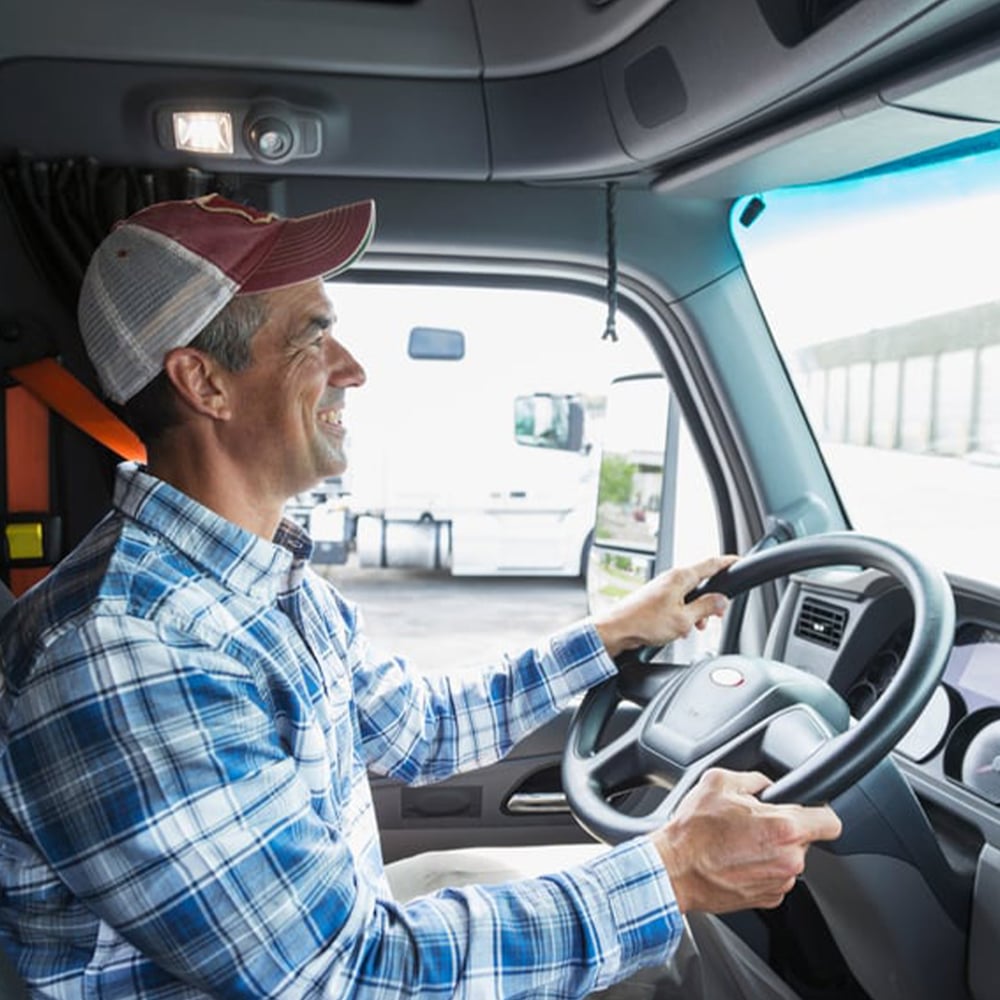 smiliing-truck-driver-in-cab-behind-wheel